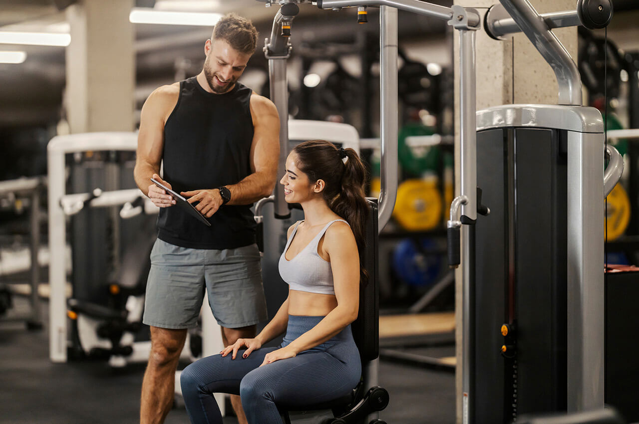 Was Menschen langfristig an ein Fitnessstudio bindet, sind vor allem Vertrauen, eine persönliche Ansprache und das Gefühl, wirklich gesehen zu werden Mann und Frau im Gym